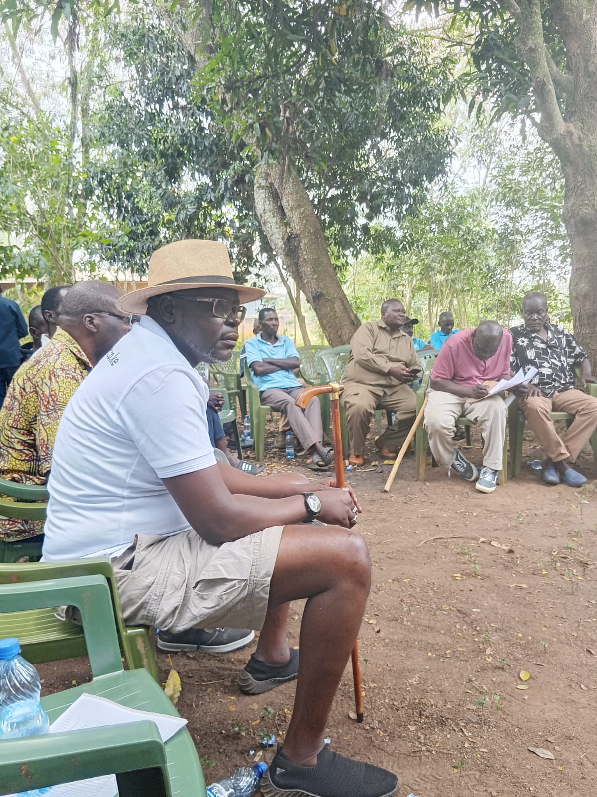 Participants seated in a shaded outdoor meeting